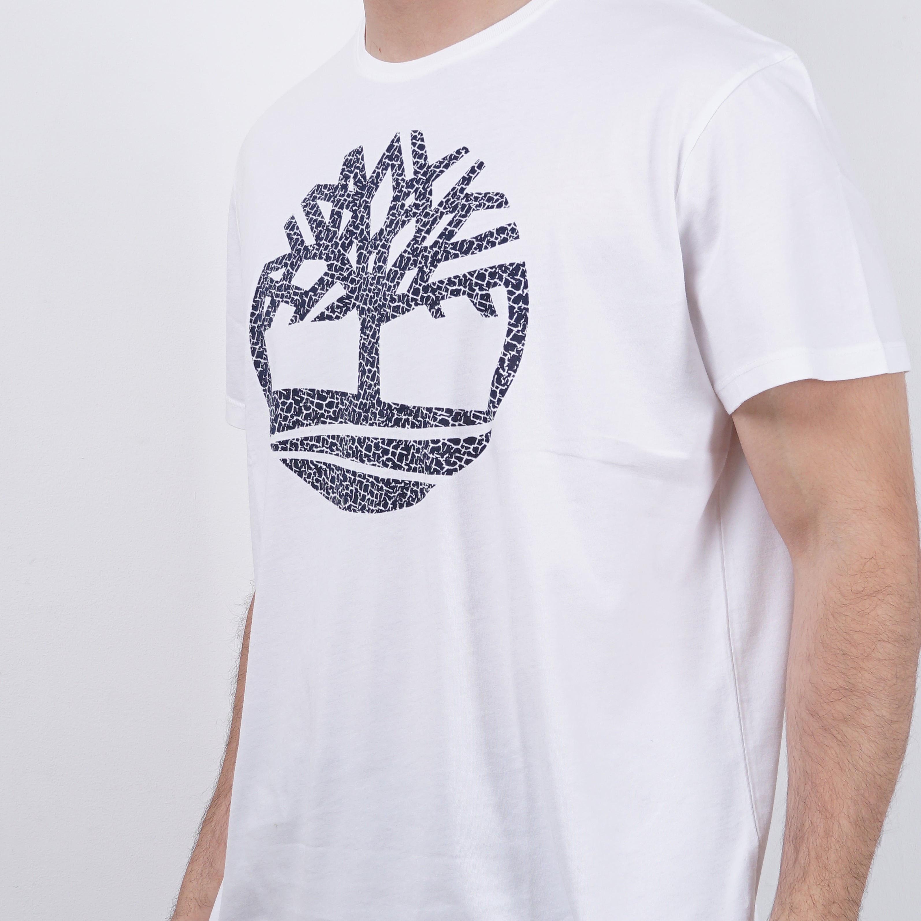 Man wearing white T-shirt with abstract Timberland logo design, fashion apparel on white background.