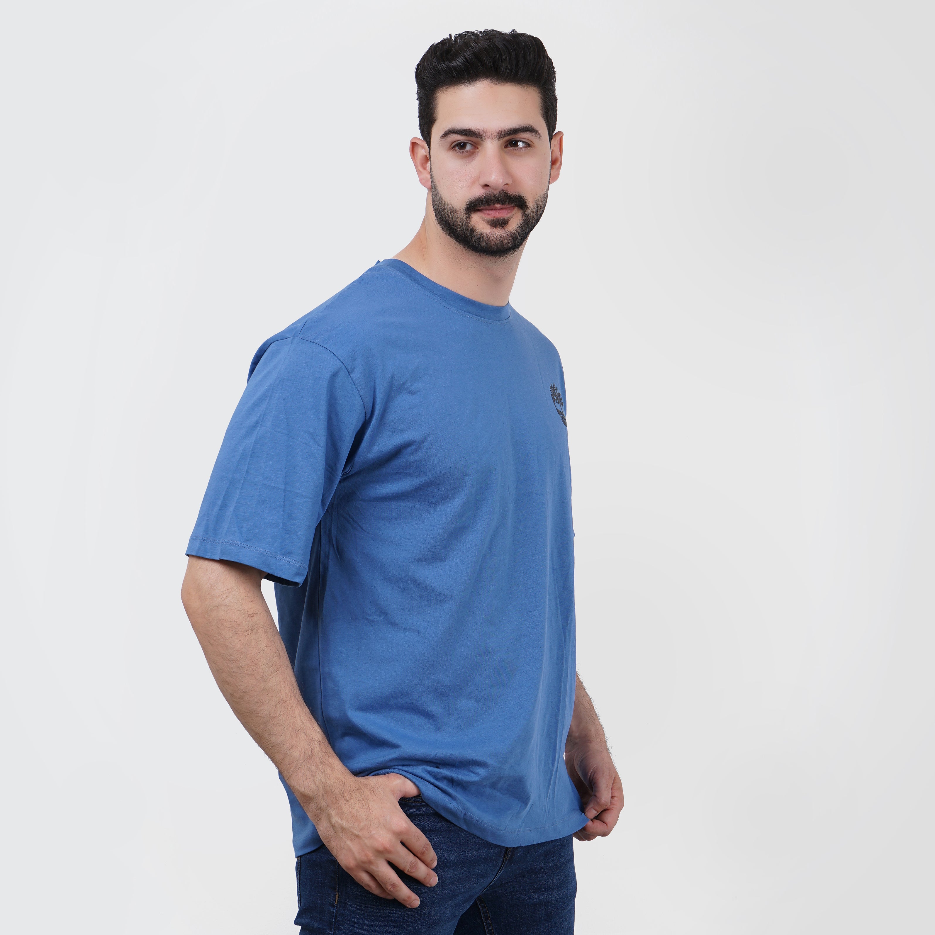 Man in blue Timberland t-shirt looking at camera on a white background.