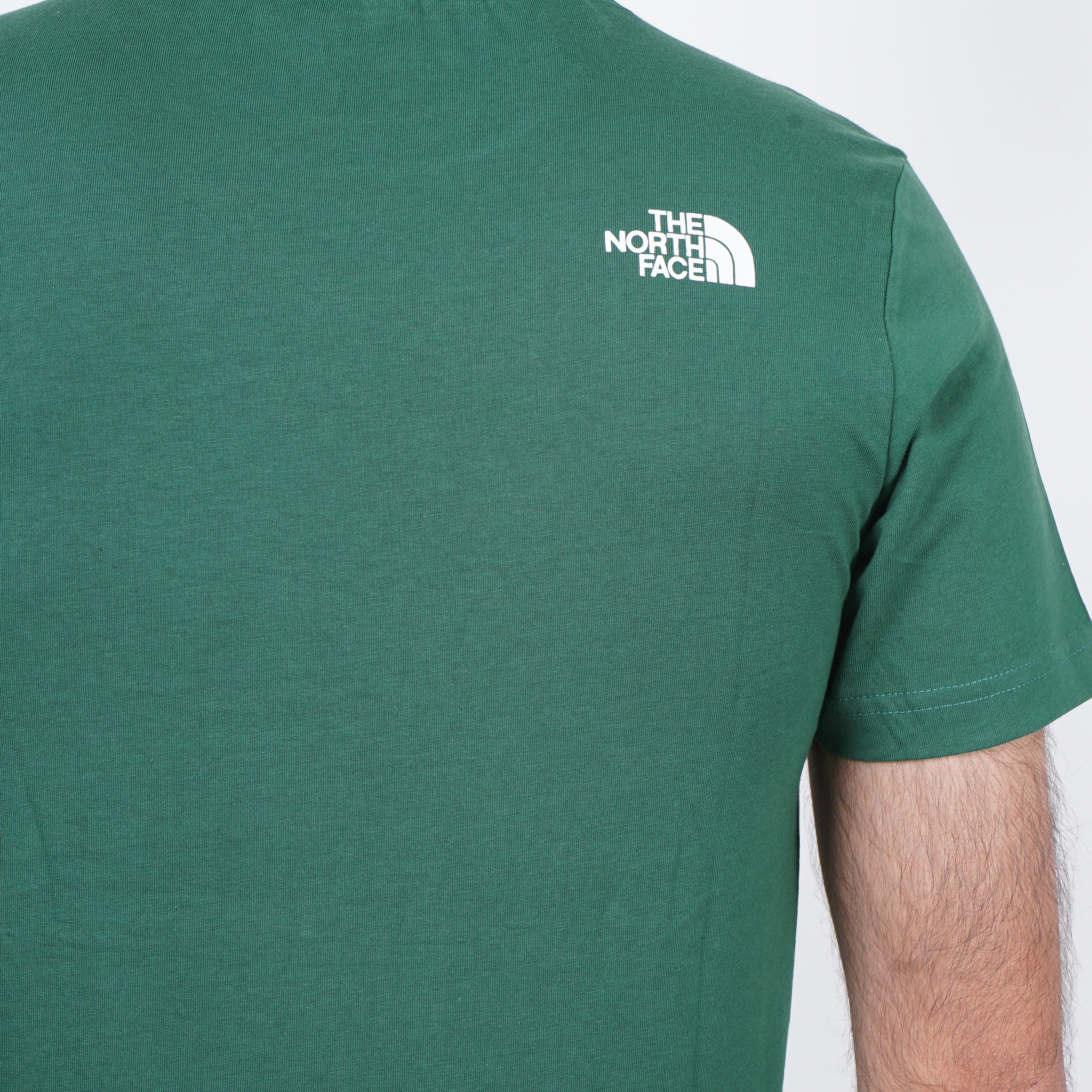 Green t-shirt with a The North face logo on the shoulder against a white background.