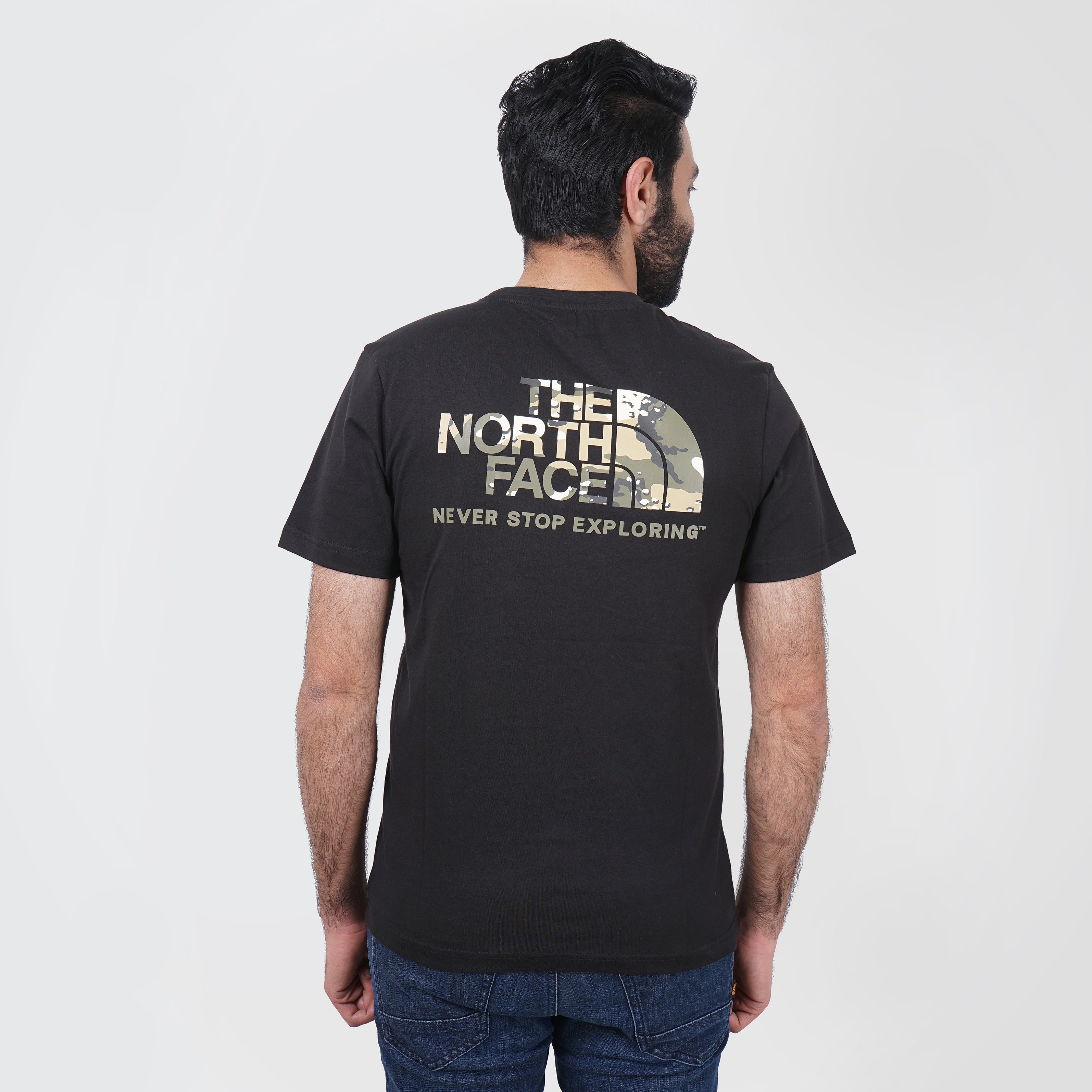 Man wearing a black North Face t-shirt with logo and 'Never Stop Exploring' slogan on the back.