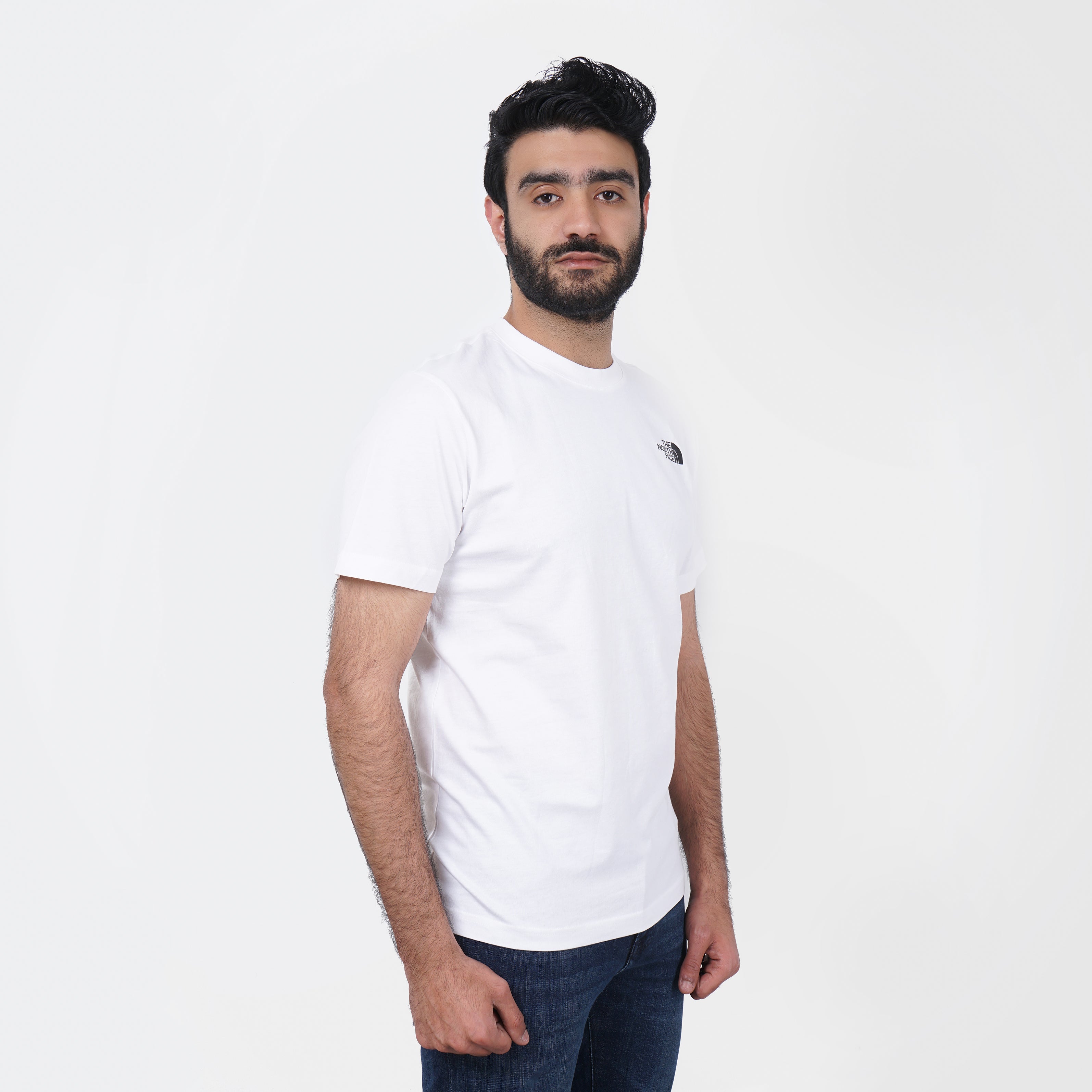 Man wearing a plain white North Face t-shirt and jeans standing against a white background.