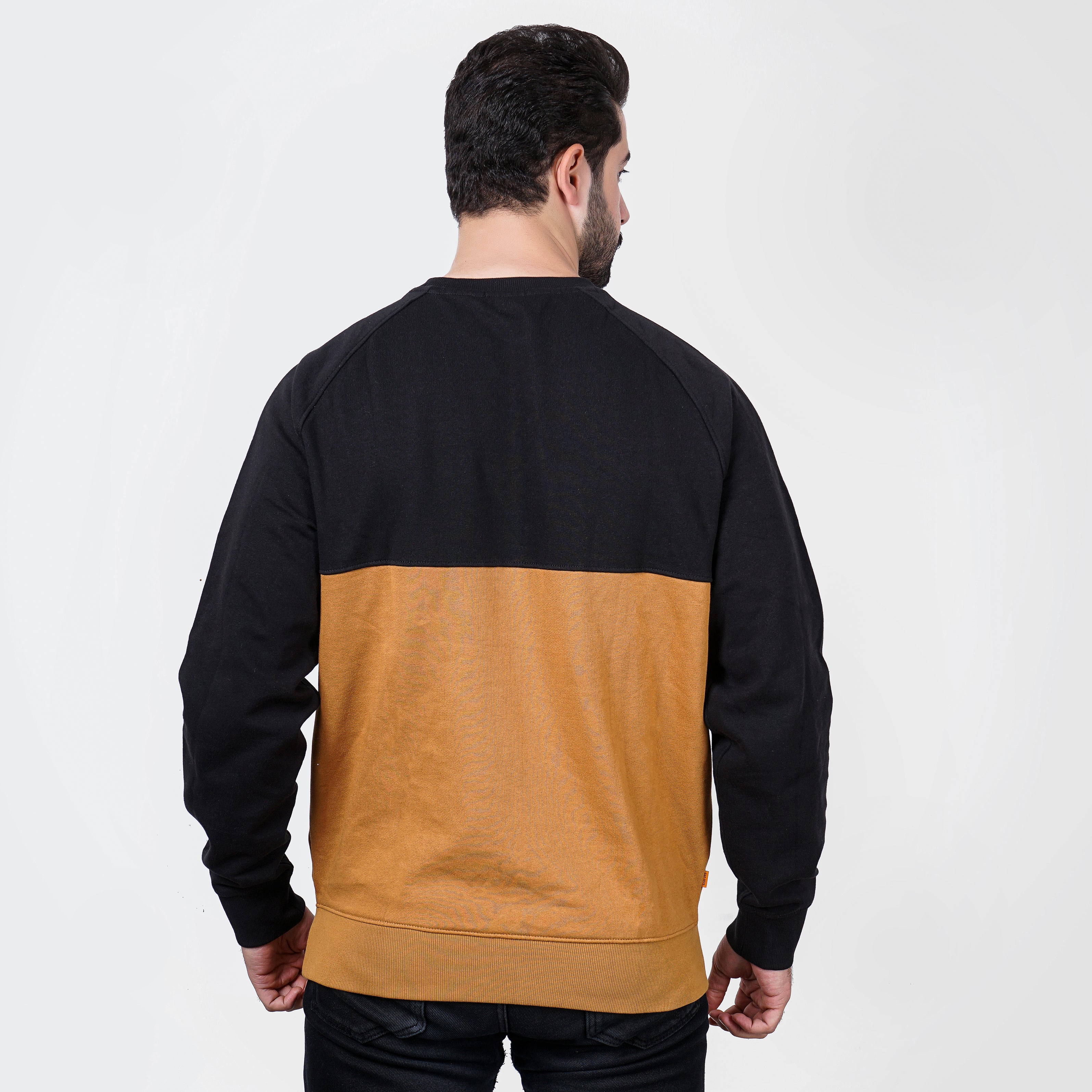 Man wearing black and tan color block Timberland sweatshirt, rear view, on white background.