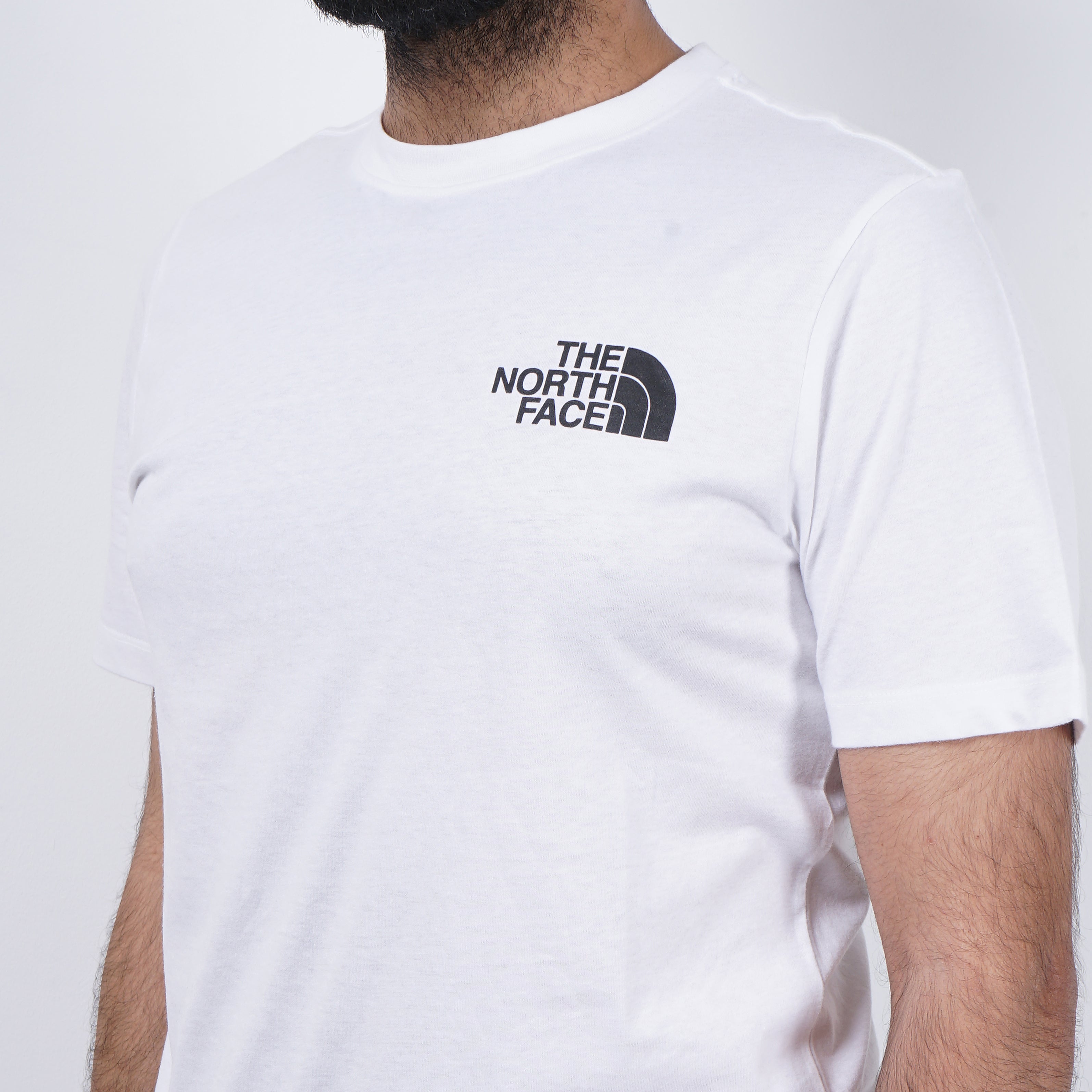 Man wearing a white The North Face t-shirt with the logo on the chest.