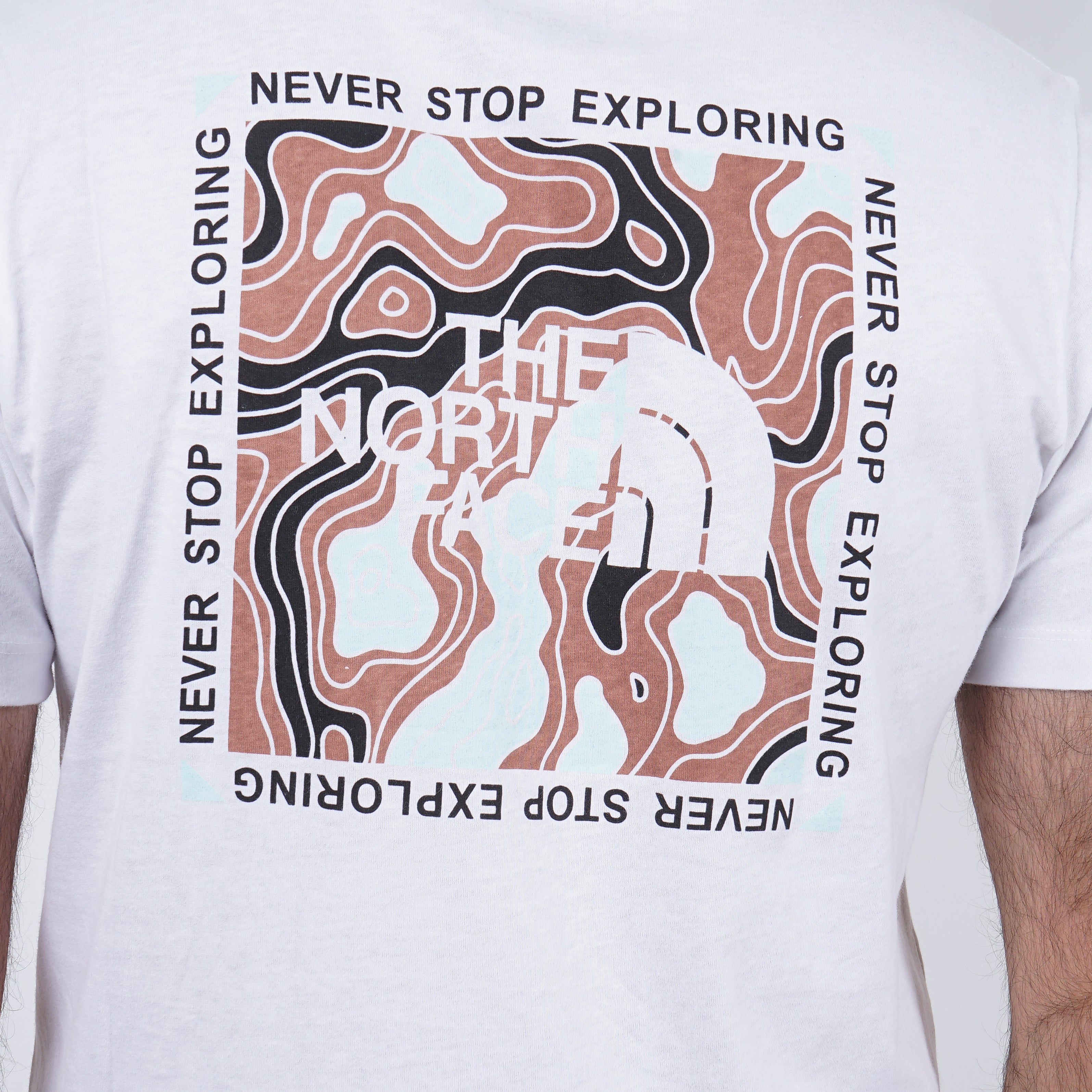 "Close-up of a white The North Face T-shirt with a 'Never Stop Exploring' logo design."