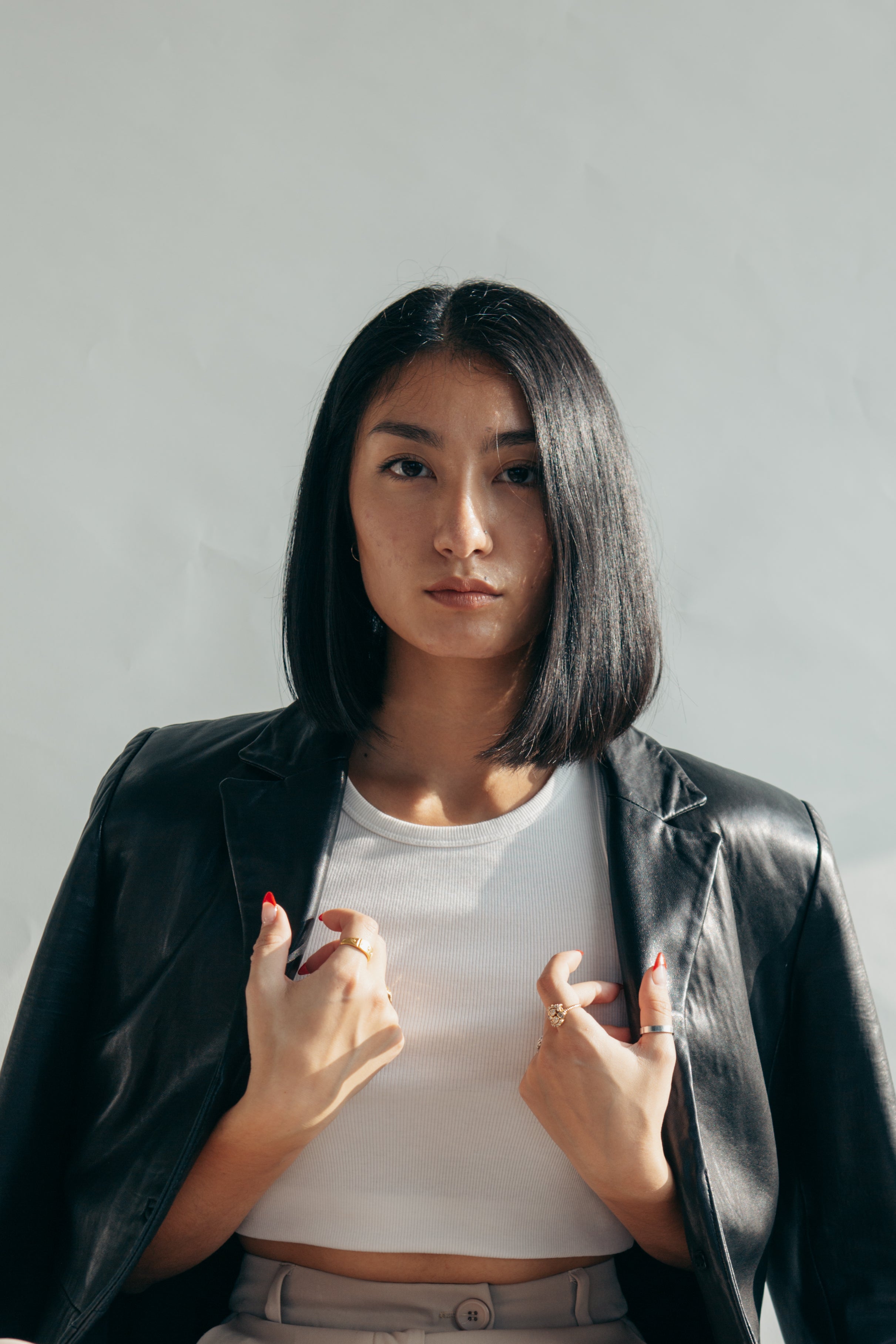 Confident woman in white top and black leather jacket with hands on collar