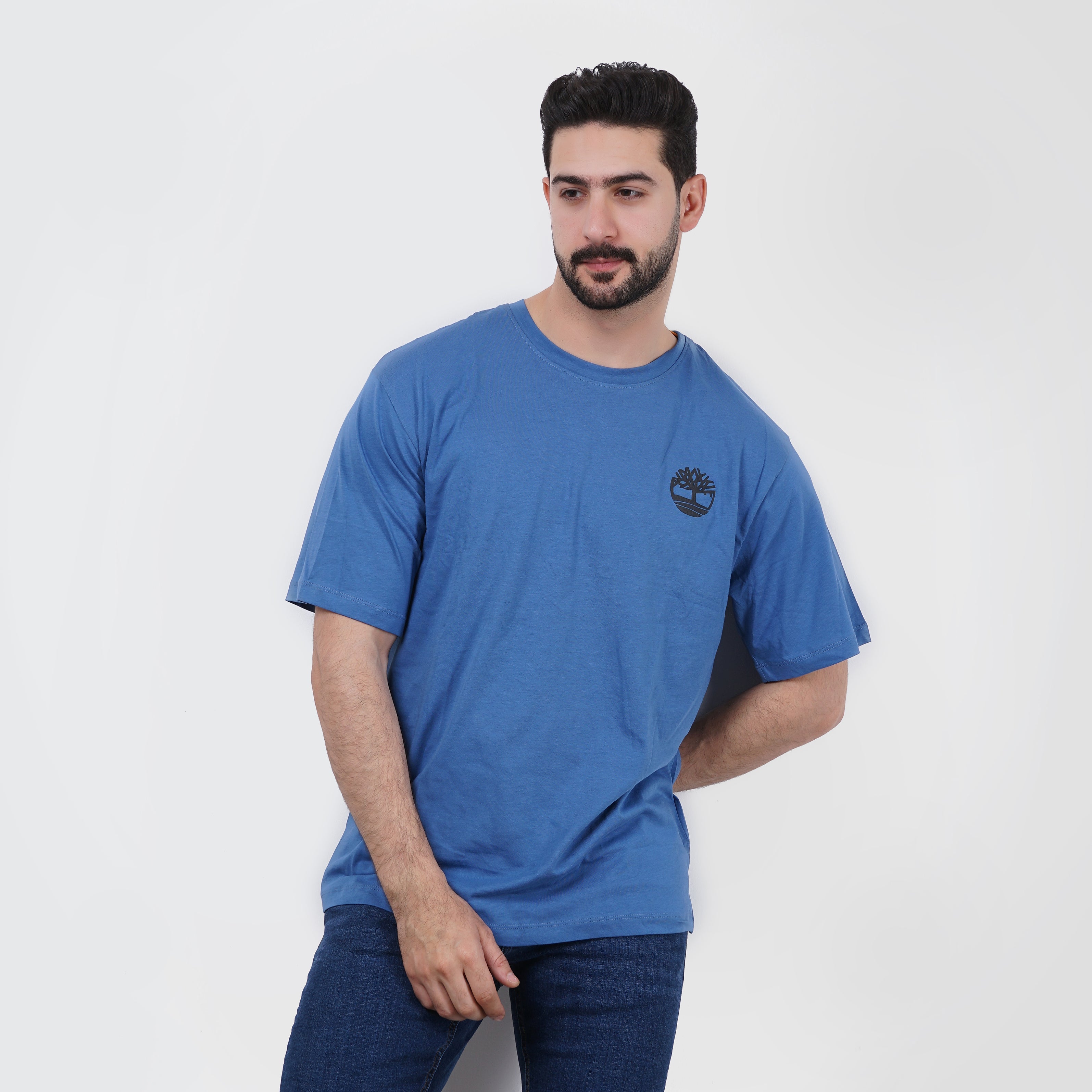 Man modeling a blue casual Timberland t-shirt and jeans, isolated on white background.