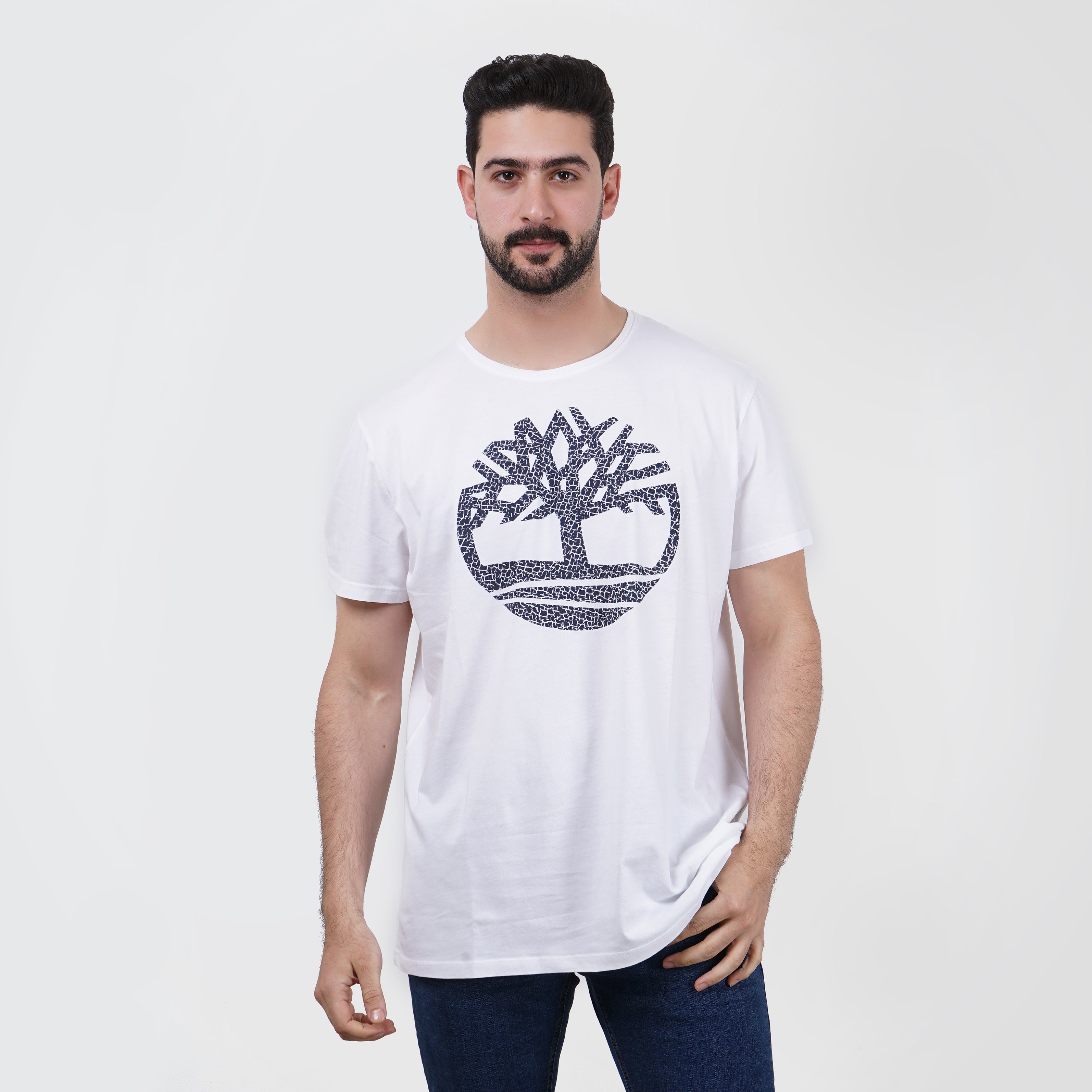 Man in white graphic t-shirt with Timberland logo design, casual style.